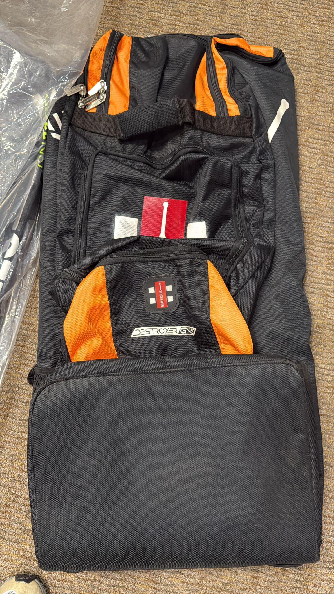 Black and orange backpack with visible branding on a carpeted floor